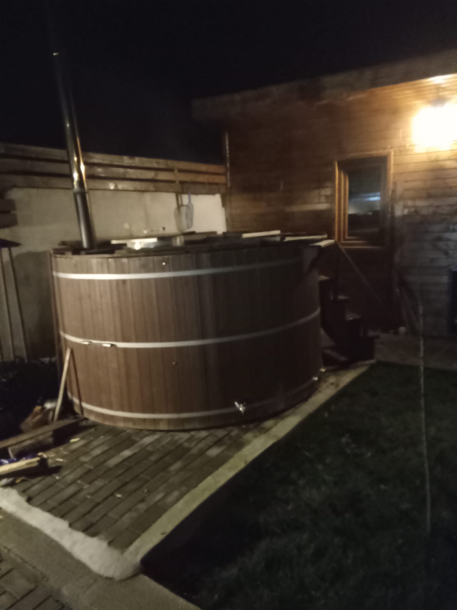 Ciubăr încălzit cu lemne, luminat noaptea, lângă cabana de lemn