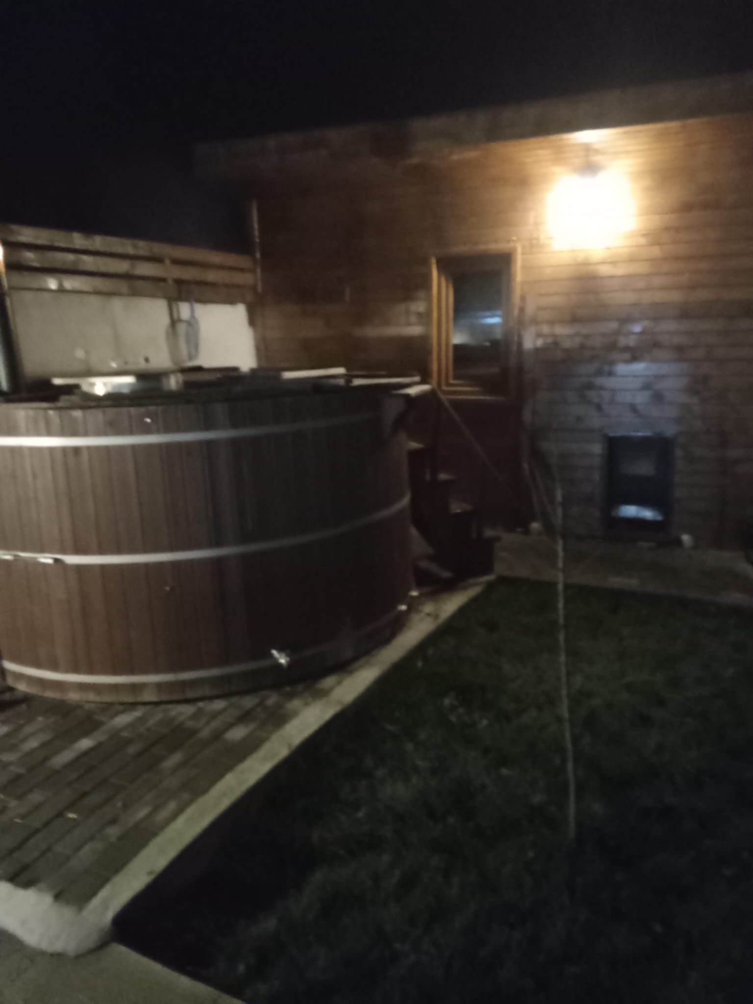 Ciubăr din lemn încălzit cu lemne, în curte, seara