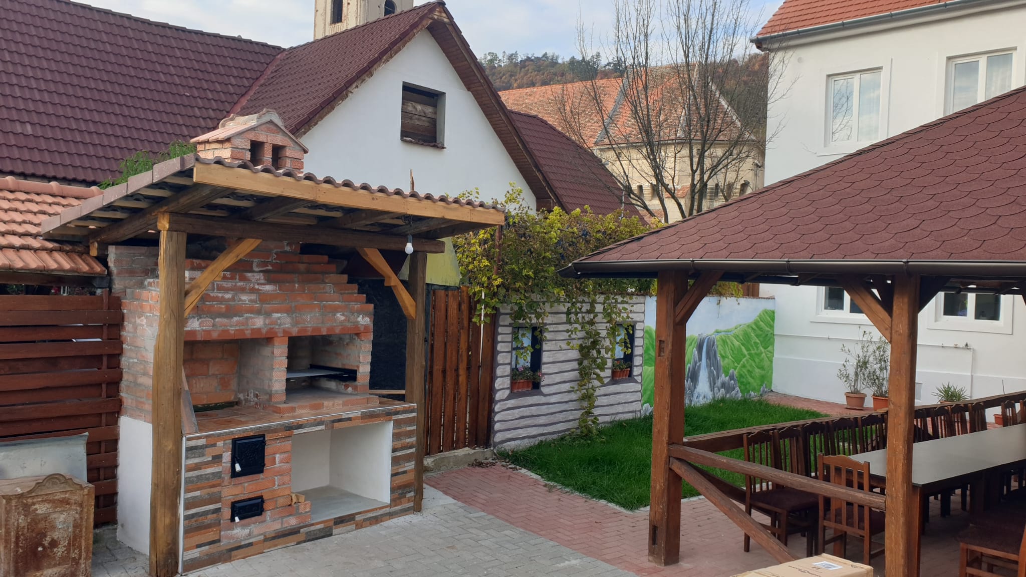 Grătar zidit din cărămidă, sub pergolă de lemn, în curte
