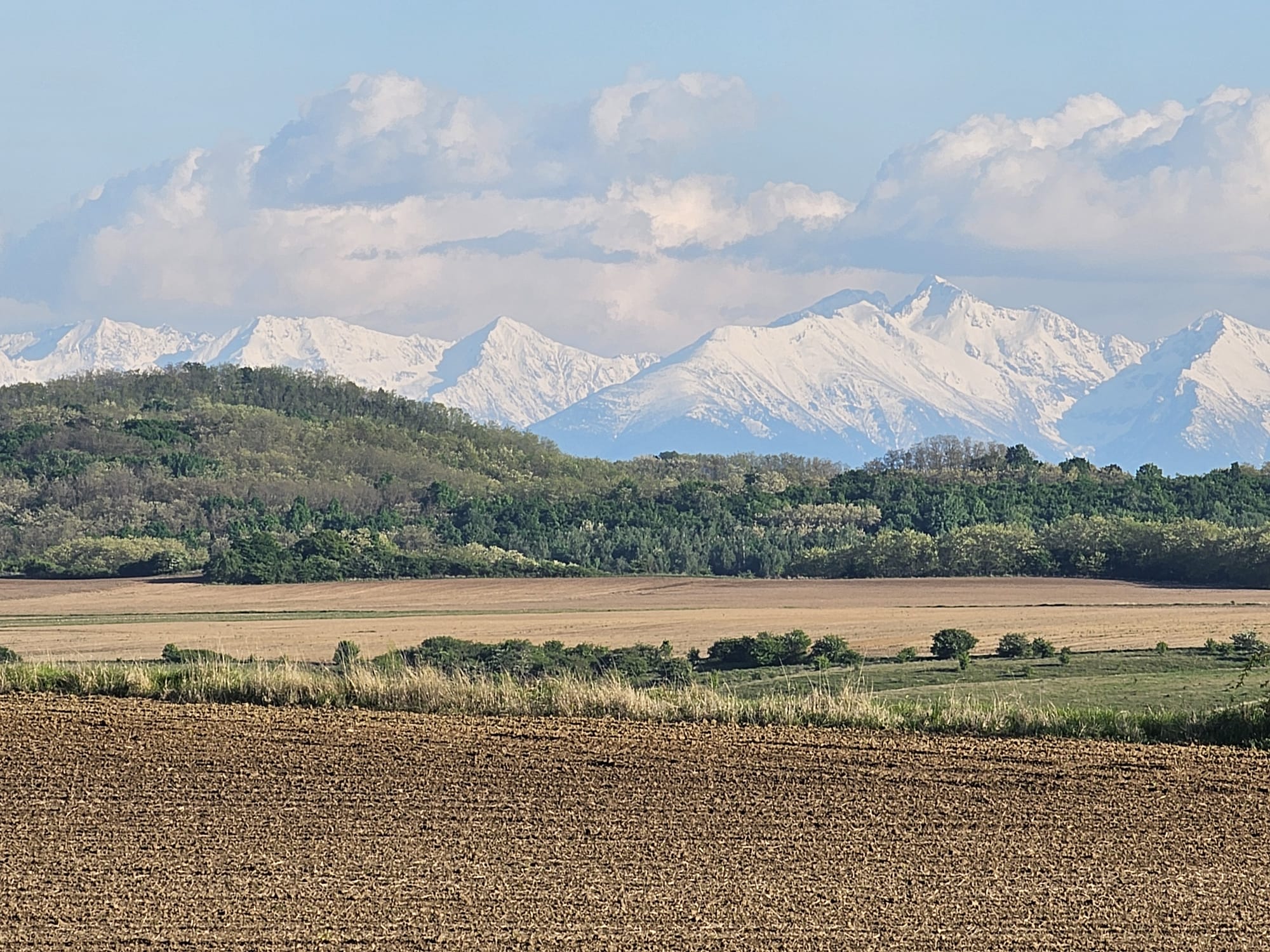 Panoramă cu lanț muntos și câmp arat