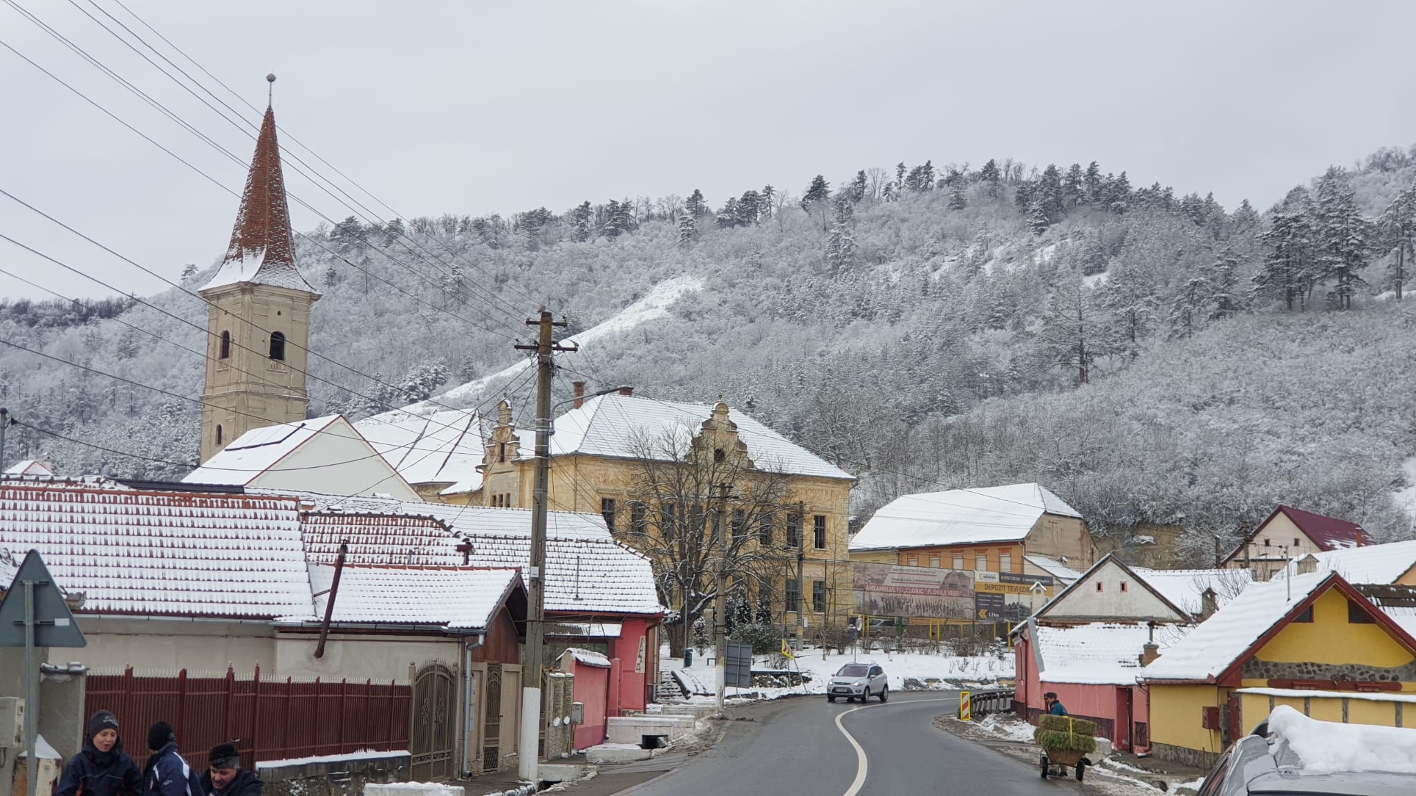 Vedere de iarnă asupra satului, cu acoperișuri și deal acoperite de chiciură
