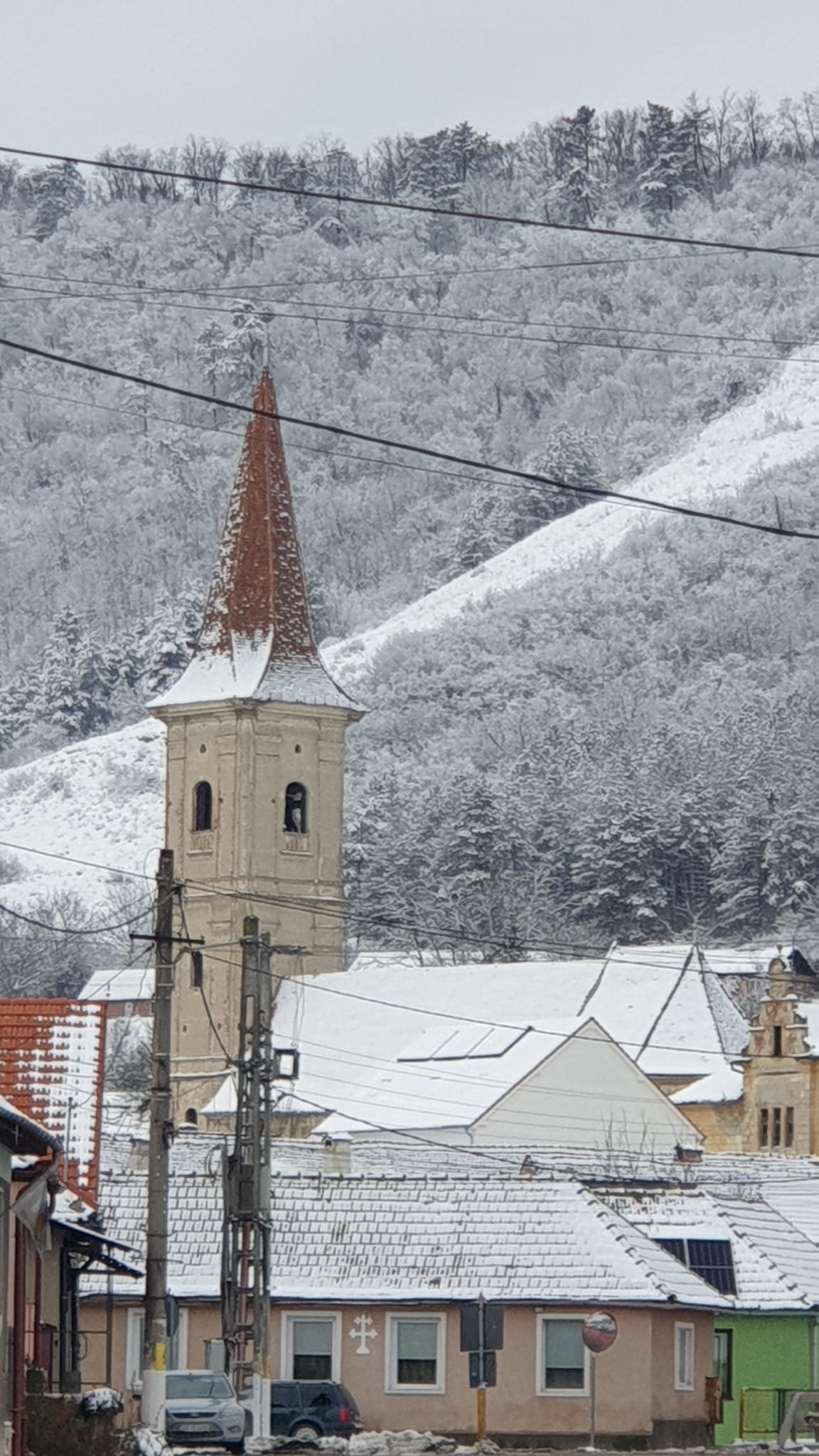 Turnul bisericii săsești, acoperit parțial de zăpadă, deal cu chiciură