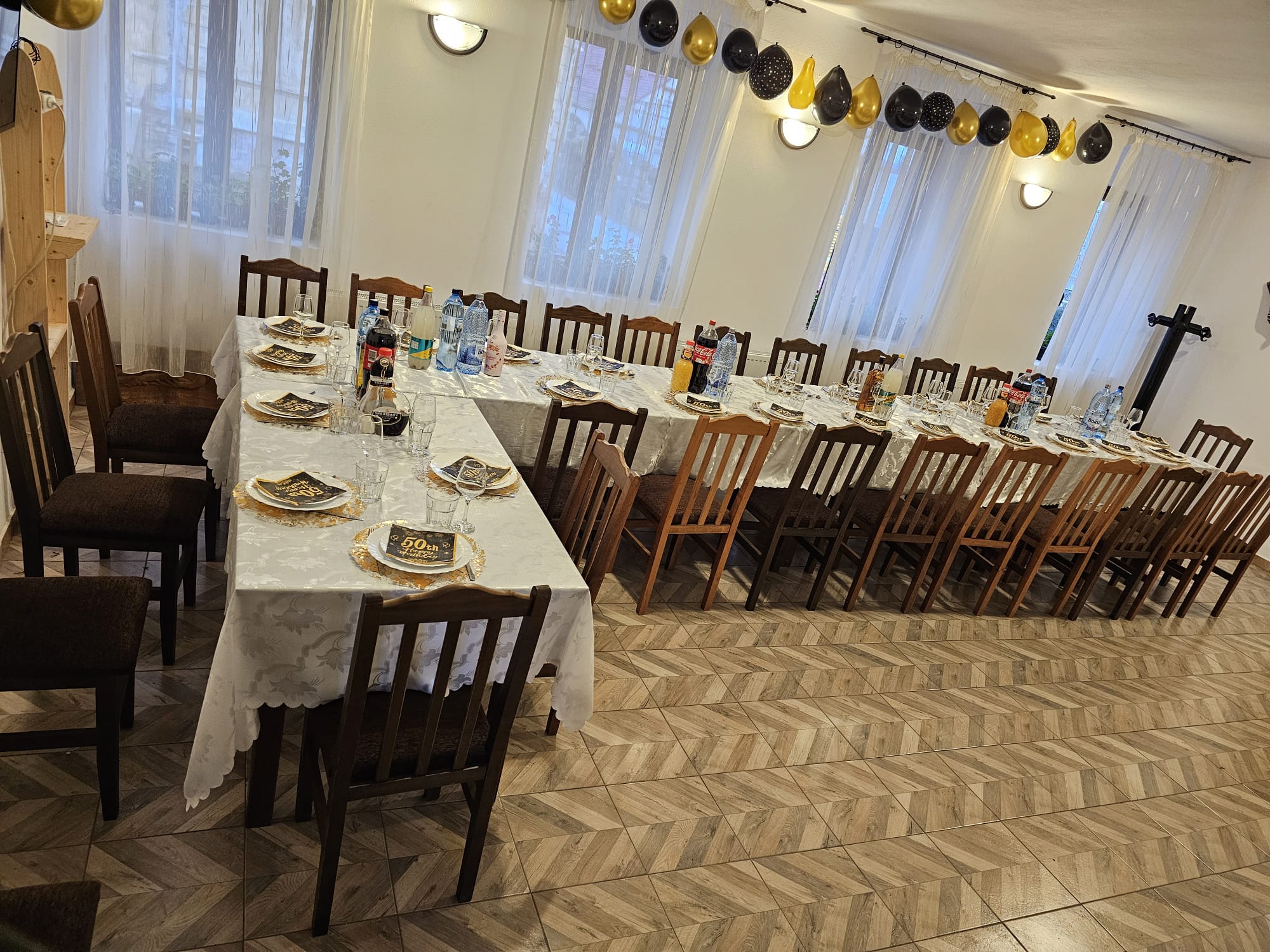 Sală amenajată pentru un eveniment, cu mese lungi aranjate