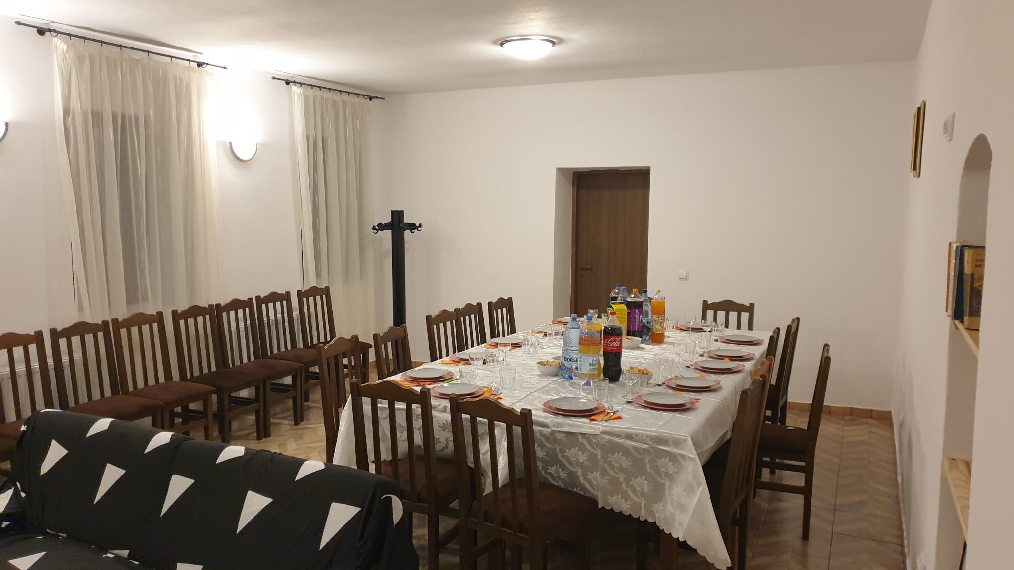 Sufragerie cu masă lungă, firidă cu cărți și canapea
