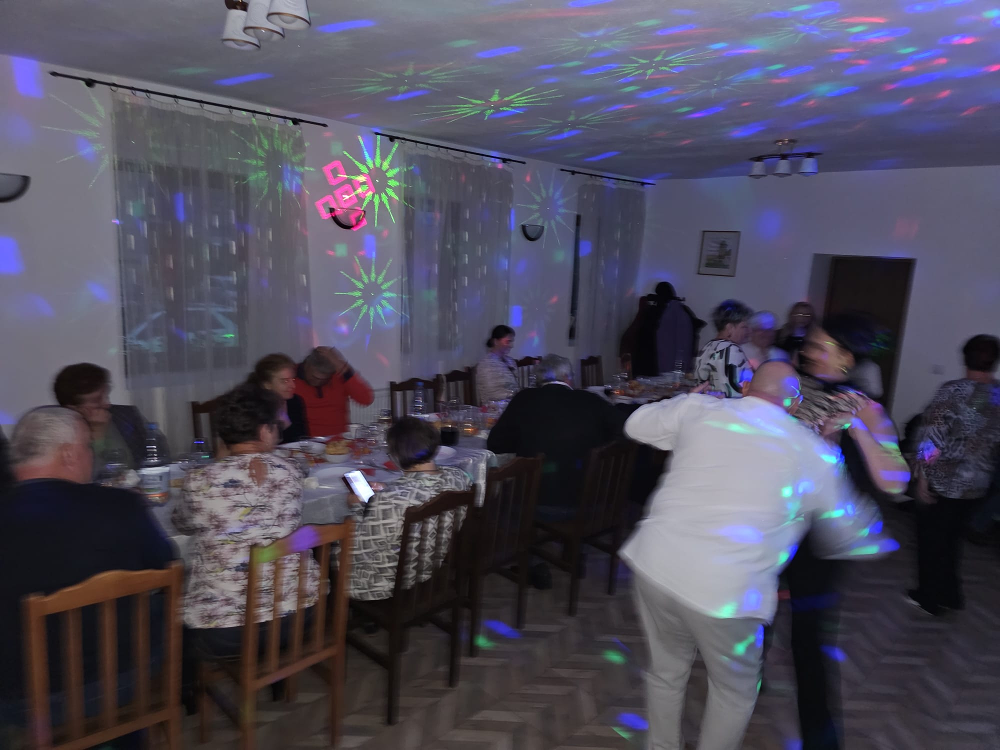 Oaspeți petrecând seara sub lumini colorate, în salon